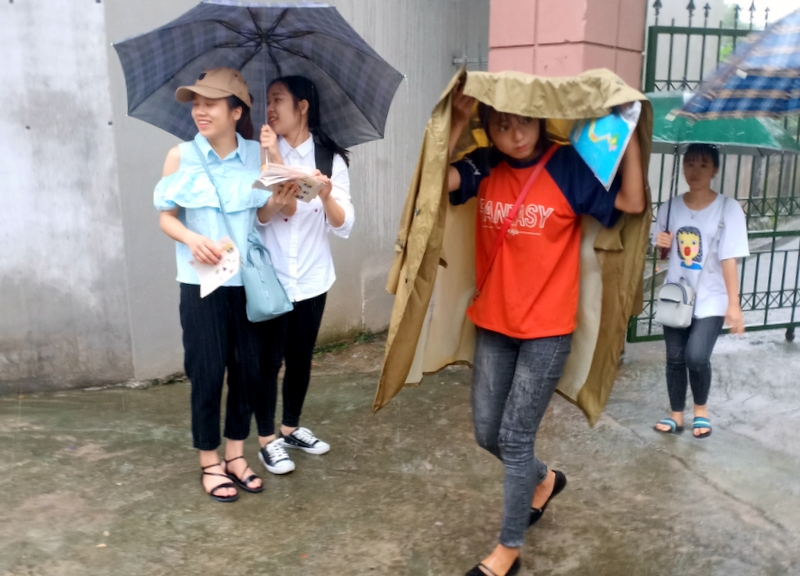 Các sĩ tử bạn che ô, bạn trùm áo mưa rời khỏi điểm thi THPT Bình Liêu sau khi hoàn thành bài thi môn Ngữ văn.