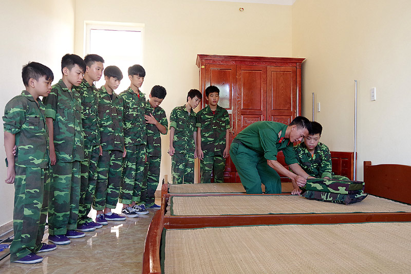 Cán bộ Trường Quân sự tỉnh hướng dẫn các chiến sĩ nhí gấp nội vụ sáng.