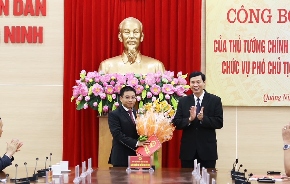 Đồng chí Nguyễn Đức Long trao quyết định và tặng hoa chúc mừng đồng chí Nguyễn Văn Thắng.