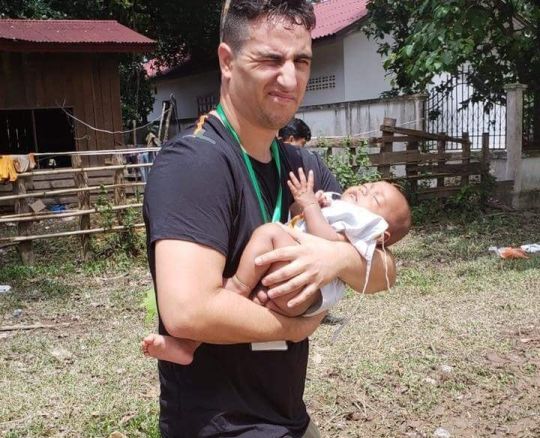 Tình nguyện viên người Mỹ Michael Alfaro đã đi bộ bé em bé trên đoạn đường 1 km đến cơ sở y tế. Ảnh: Metro