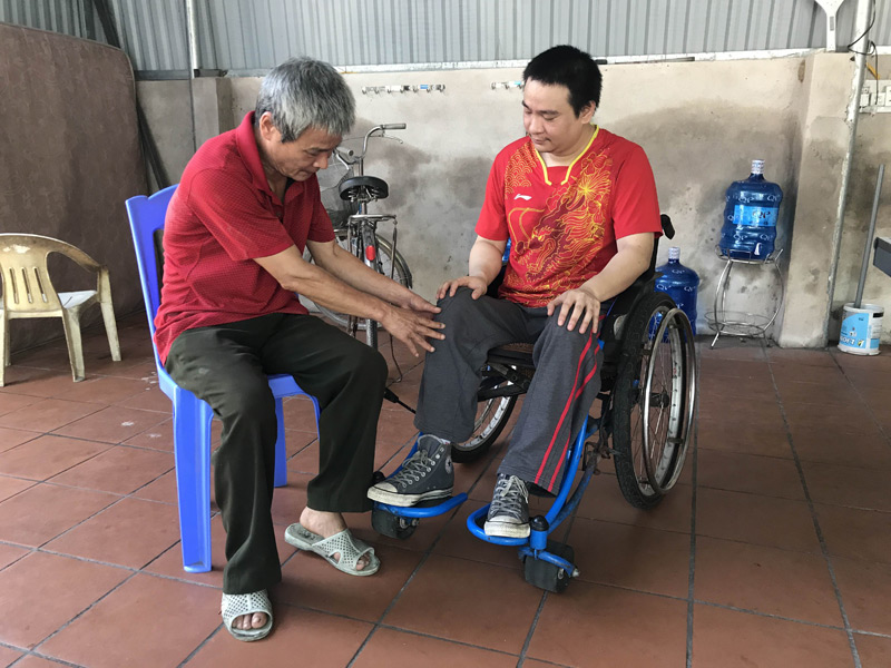 Anh Phạm Minh Đức đang được cha mình kiểm tra khả năng vận động của đôi chân 