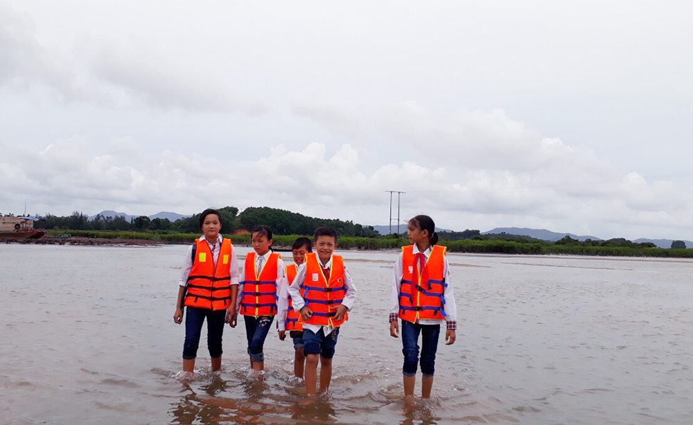Học sinh khối THCS sồng ở thôn đảo Hà Loan hằng ngày phải lội nước đến trường.