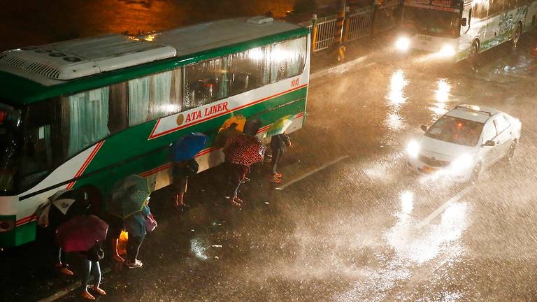 Người dân Manila di chuyển trong điều kiện thời tiết mưa gió. (Ảnh: AP)