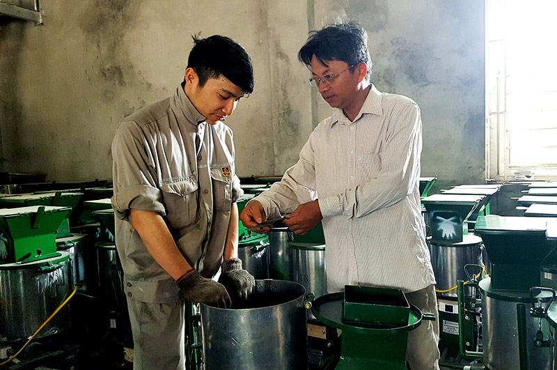 Đinh Văn Giang (bên phải) chỉ bảo kinh nghiệm sản xuất, chế tạo máy cho người lao động làm việc tại cơ sở chế tạo máy của gia đình.