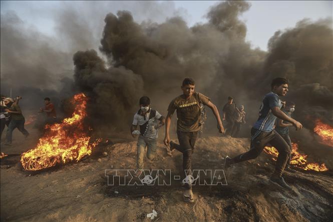 Người biểu tình Palestine chạy trốn làn đạn hơi cay của binh sĩ Israel trong xung đột tại khu vực biên giới với Dải Gaza ngày 28/9/2018. Ảnh: THX/TTXVN