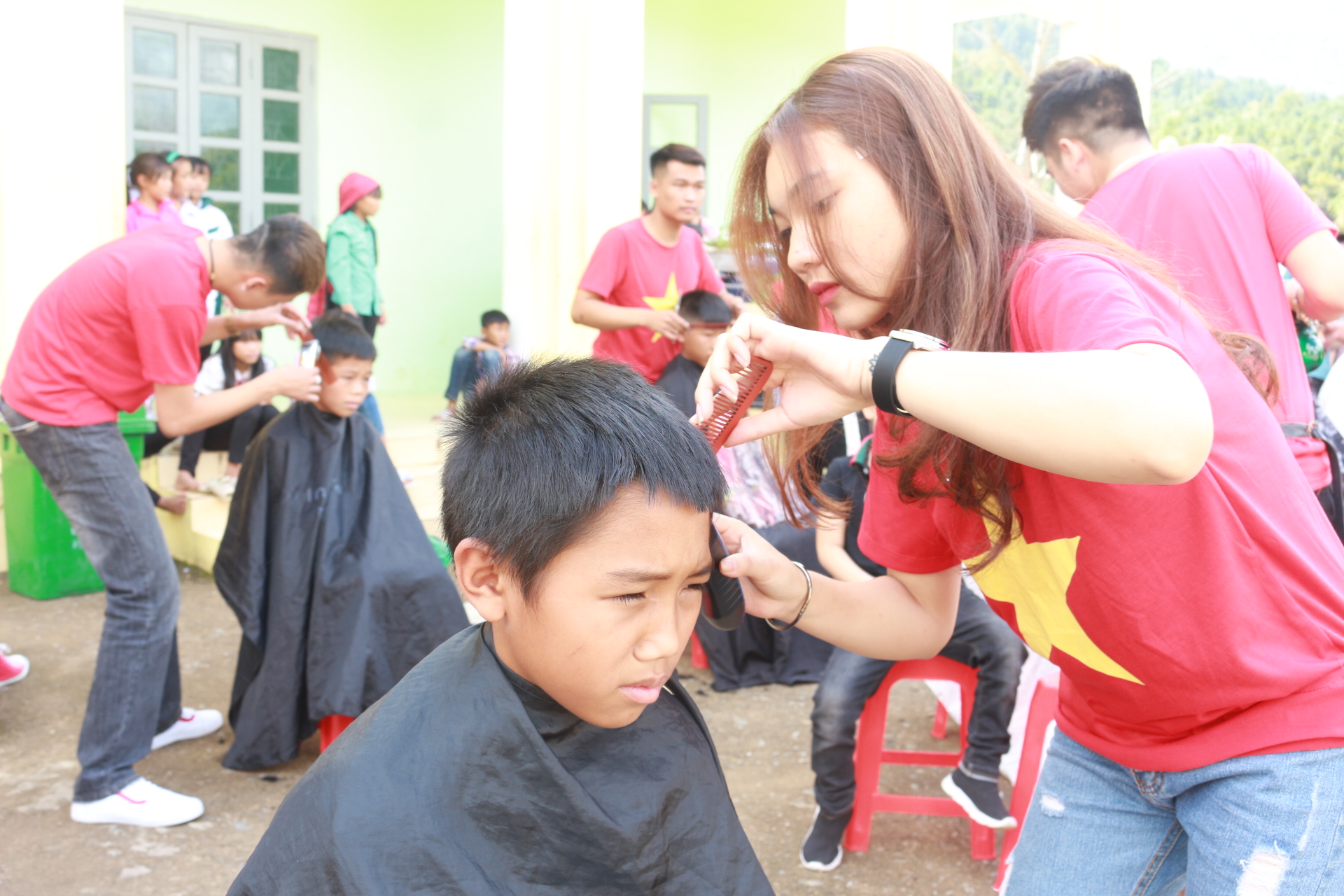Một học sinh chăm chú khi được cắt tóc.