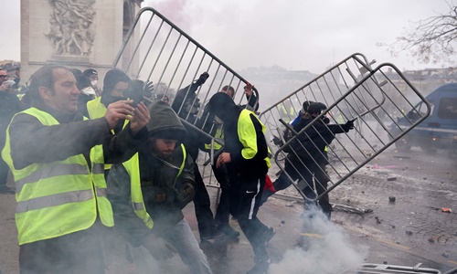 Người biểu tình xô đổ rào chắn do cảnh sát dựng lên trên đại lộ Champs-Élysées. Ảnh: AFP.
