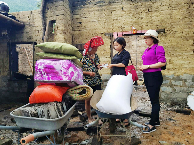 Chị Lã Thị Liên (đứng giữa) trao vật dụng hỗ trợ cho gia đình bà Thìn bị cháy nhà ở Bình Liêu.