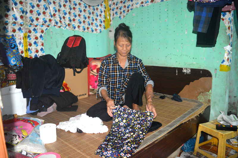 Bà Chu Thị Khang sắp xếp đồ trong căn phòng ẩm thấp ở khu trọ.