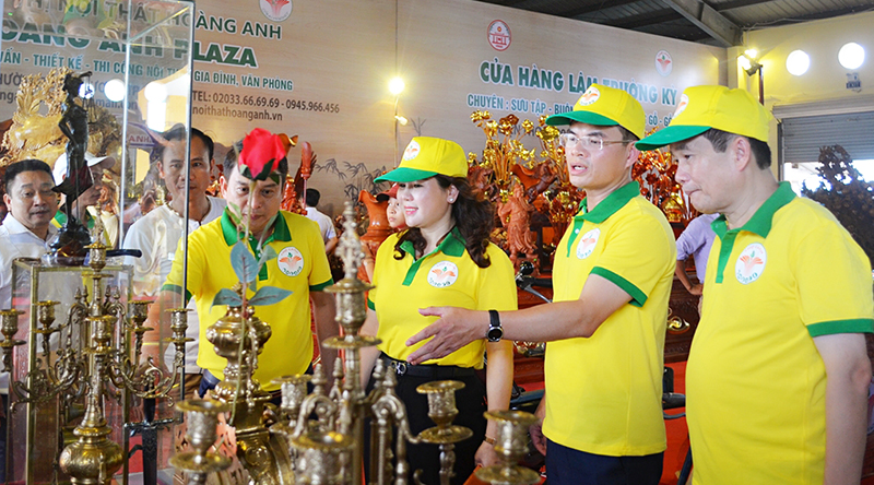 Chủ tịch UBND Nguyễn Mạnh Hà giới thiệu với các đại biểu gian hàng đồ cổ, đồ cũ bày bán tại chợ Cảnh Uông Bí