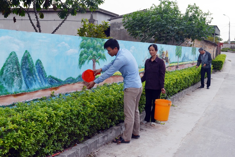 Nguyễn Thanh Tùng cùng người dân tham gia chăm sóc cây xanh tại đoạn đường mẫu của thôn Khê Thượng (xã Việt Dân, TX Dông Triều)