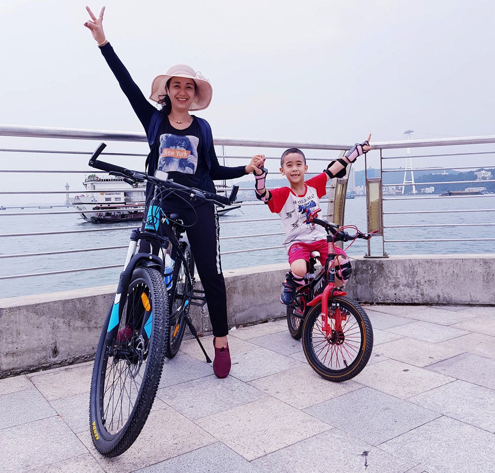 Chị Hồ Thị Vân Anh đi dạo bằng xe đạp ven bờ biển Hạ Long cùng con trai.