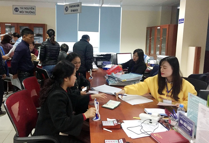 Cán bộ Trung tâm HCC TP Hạ Long hướng dẫn người dân làm thủ tục hành chính liên quan đến lĩnh vực tài nguyên môi trường. 