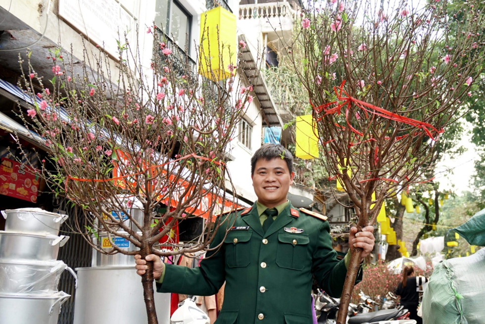 Một sĩ quan quân đội quyết định mua 2 cành đào lớn về cho gia đình sau một vòng ngắm các loại hoa ở chợ Hàng Lược. Ảnh Ngọc Thắng