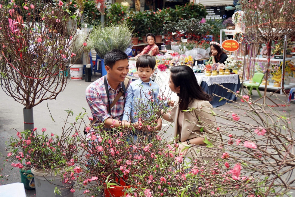 Gia đình anh Tuấn, chị Linh (Hà Nôi) đưa con trai tới chợ Hàng Lược vừa chọn đào Tết cho gia đình vừa du xuân trong những ngày cuối năm thảnh thơi. Ảnh Gia Hân