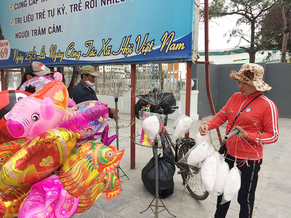 Chị Nguyễn Thị Dung, quê ở Thanh Hóa, bên gánh hàng rong bán bóng bay, kẹo bông.
