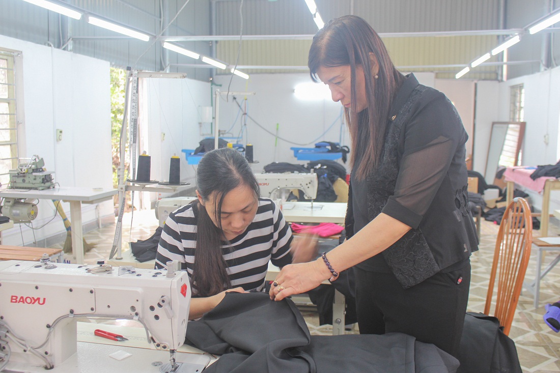 Chị Đào Thị Hà Hải (người đứng) hướng dẫn tay nghề cho chị em làm việc tại xưởng may của gia đình.