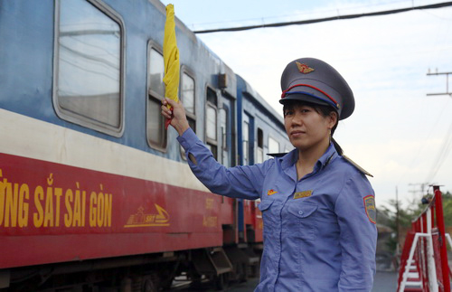 Chị Minh ra hiệu cờ thông tàu tại chốt gác chắn Hãng Dầu, TP Biên Hòa. Ảnh: Phước Tuấn.