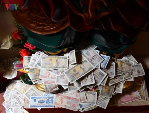 Người đi lễ đặt tiền lẻ dưới chân tượng Phật.