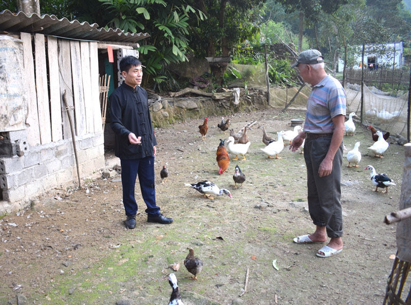Anh Sằn A Dẩu, người có uy tín thôn Khe Lặc, xã Đại Thành (bên trái) hướng dẫn bà con làm chuồng trại hợp vệ sinh và phát triển chăn nuôi