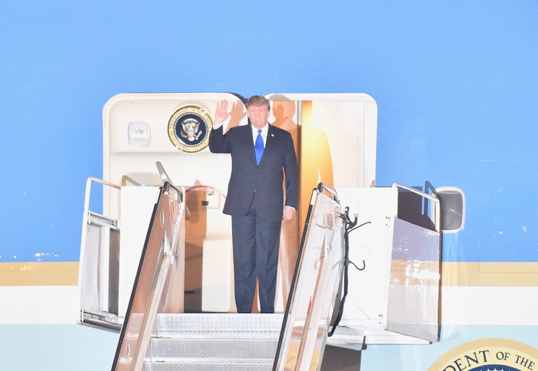 Bước xuống cầu thang máy bay, Tổng thống Donald Trump vẫy chào đông đảo người đang có mặt, chào mừng ông tại sân bay. Ảnh VGP/Nhật Bắc