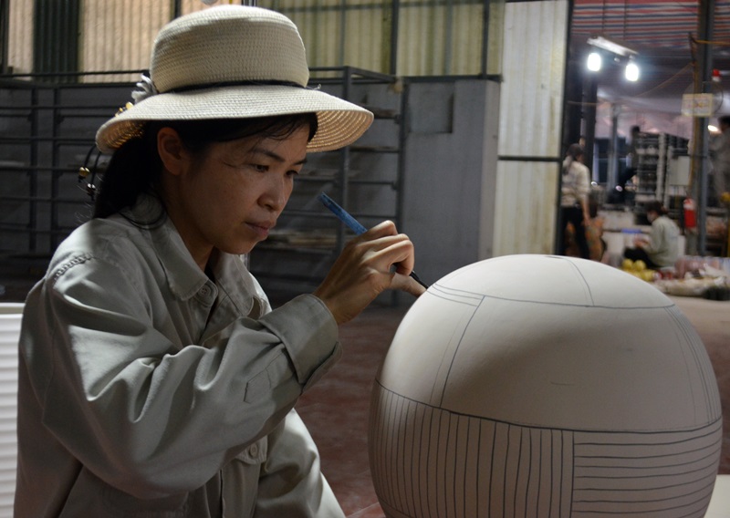 Một nữ lao động chăm chú kẻ họa tiết trên sản phẩm gốm.