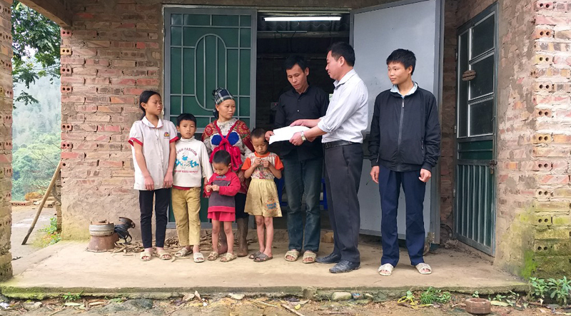 Anh Nông Thanh Sơn, cán bộ Tư pháp xã Đồng Tâm trao giấy khai sinh cho các con của vợ chồng ông Chíu Chăm Cắm.