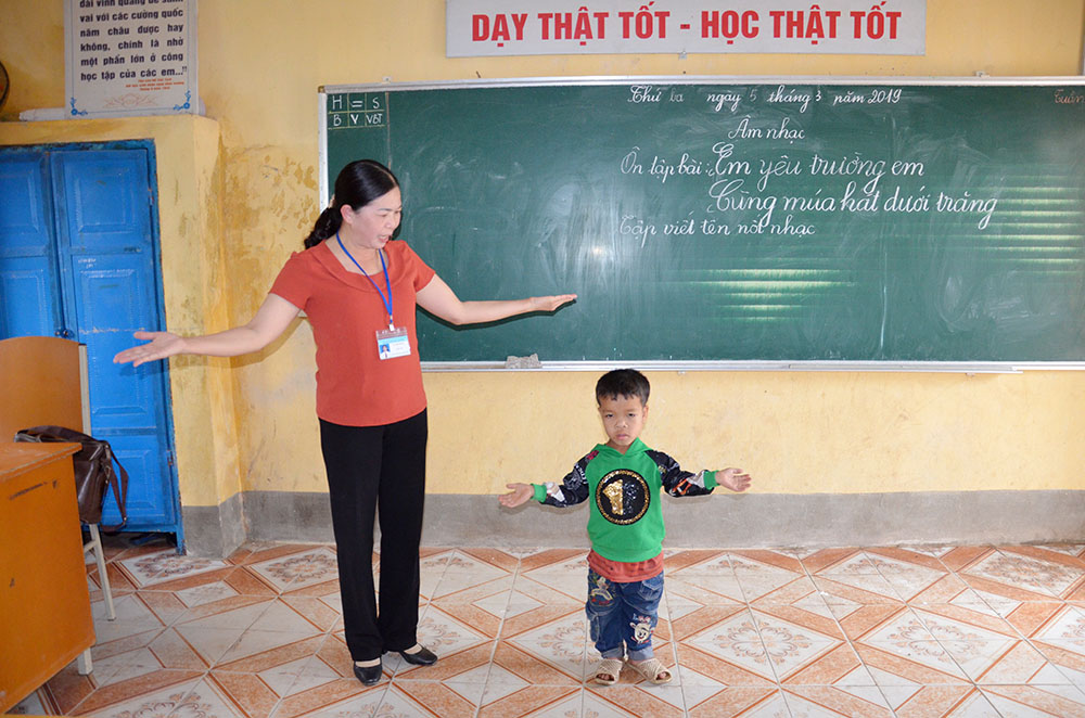 Cô giáo Lã Thị Nhung, giáo viên dạy cơ sở Khe Tâm, Trường Tiểu học Nam Sơn, huyện Ba Chẽ dạy em Vi Xuân Cảnh học nhạc.
