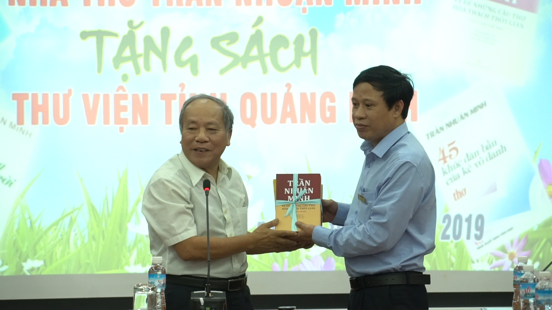 Ông Phạm Văn Triển - Phó Giám đốc phụ trách thư viện tỉnh Quảng Ninh tiếp nhận sách của nhà thơ Trần Nhuận Minh