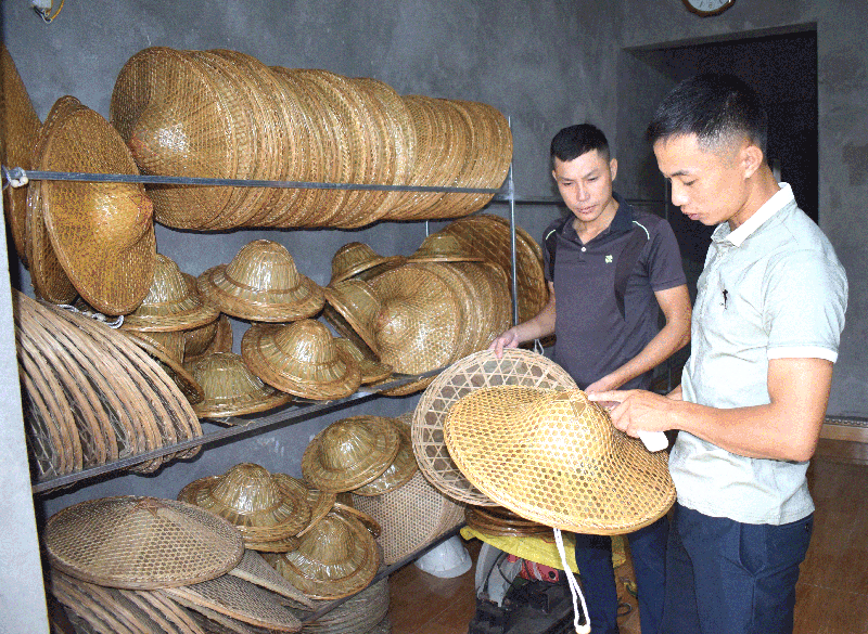 Anh Lý A Tài (bên phải) giới thiệu sản phẩm nón Đại Hiệp với khách hàng