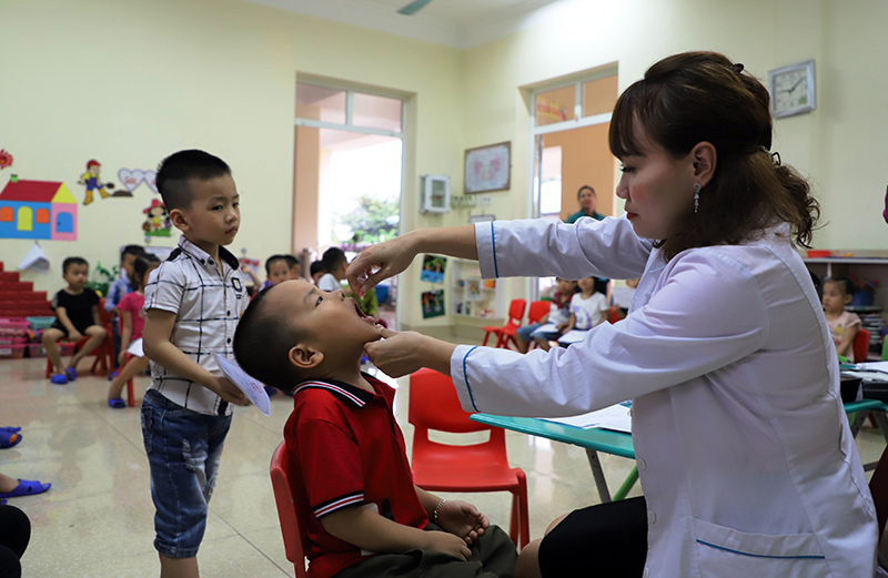 Cán bộ Trạm Y tế phường Cẩm Thủy cho trẻ uống vắc xin bại liệt bOPV tại điểm Trường mầm non hoa hồng, phường Cẩm Thủy, TP Cẩm Phả, Quảng Ninh