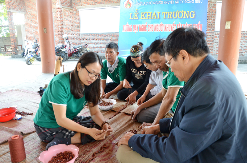 Chị Nguyễn Hải Yến, Chủ nhiệm CLB Người khuyết tật TX Đông Triều, hướng dẫn các thành viên cách đan hạt gỗ mỹ nghệ. Ảnh: Phương Thúy (CTV)