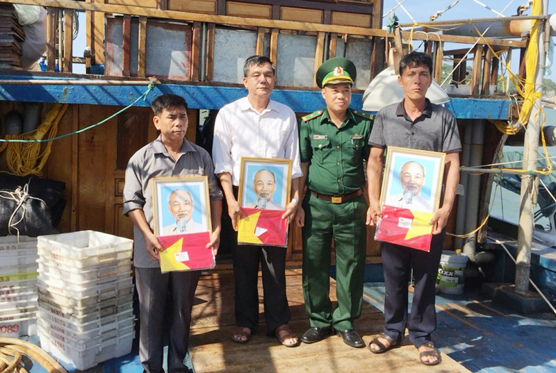Chính trị viên, Thiếu tá Trương Văn Hùng, đại diện cho Đảng ủy Đồn Biên phòng Quan Lạn tặng ảnh Bác Hồ và cờ Tổ quốc cho ngư dân huyện Vân Đồn.