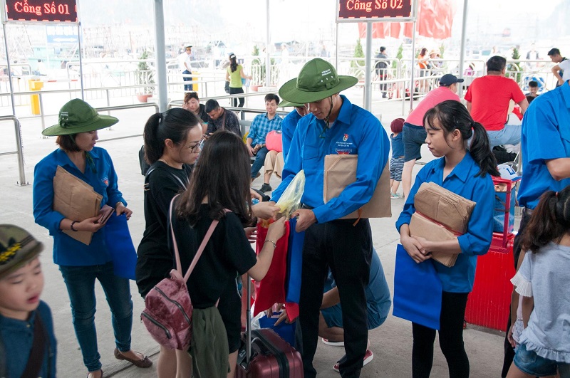 Đoàn viên, thanh niên huyện Cô Tô phát túi giấy sinh thái cho khách du lịch để thay thế túi nilon trước khi lên tàu đi ra đảo Cô Tô. Ảnh: Minh Đức