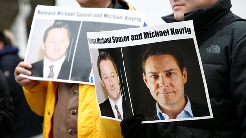 Người biểu tình cầm ảnh kêu gọi Trung Quốc trả tự do cho Michael Spavor (trái) và Michael Kovrig trên đường phố Canada hồi tháng ba. Ảnh: Reuters.