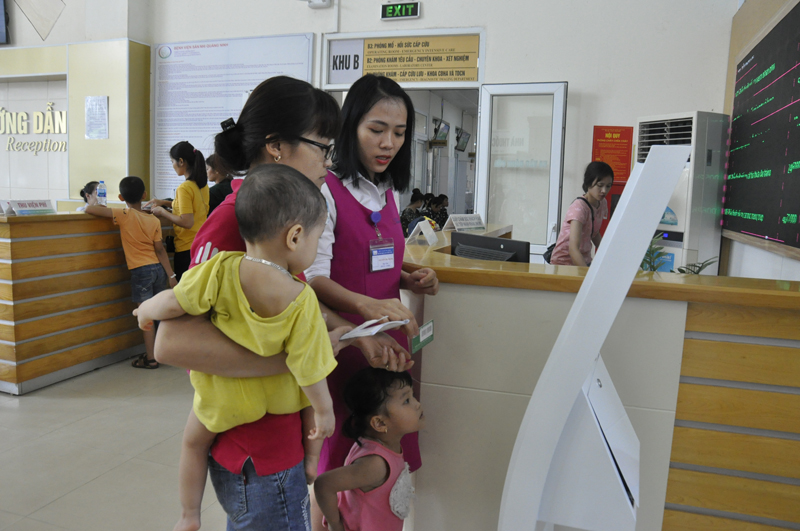 Nhân viên Bệnh viện Sản nhi tỉnh hướng dẫn người dân có BHYT quẹt thẻ đăng ký khám bệnh tại ki ốt thông minh của Bệnh viện.
