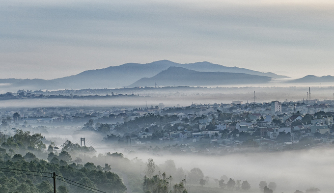 Một góc thành phố Pleiku đoạn cầu Phan Đình Phùng trong sương mù buổi sáng tháng 6. Anh Hoàng Quốc Vĩnh, một tay máy, cho biết sương hòa quyện với mây từ ngọn Hàm Rồng cao trên 1.000 m tràn xuống thung lũng tạo nên 