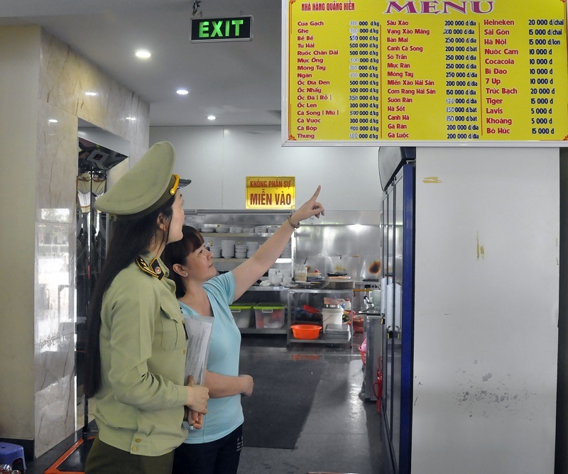 Kiểm soát viên Đội QLTT số 3 kiểm tra việc niêm yết giá bán hàng tại nhà hàng hải sản Quảng Hiền, TP Cẩm Phả.