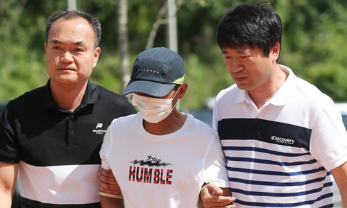 Người chồng Hàn Quốc, giữa, bị cảnh sát bắt sau khi hành hung vợ Việt hôm 4/7. Ảnh: Yonhap.