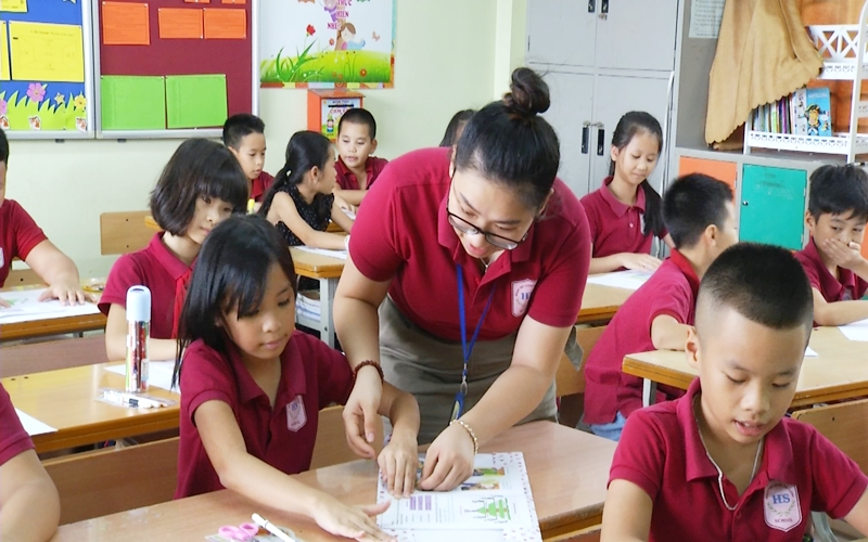 Cô giáo tỉ mỉ hướng dẫn từng em học sinh bọc vở bằng giấy
