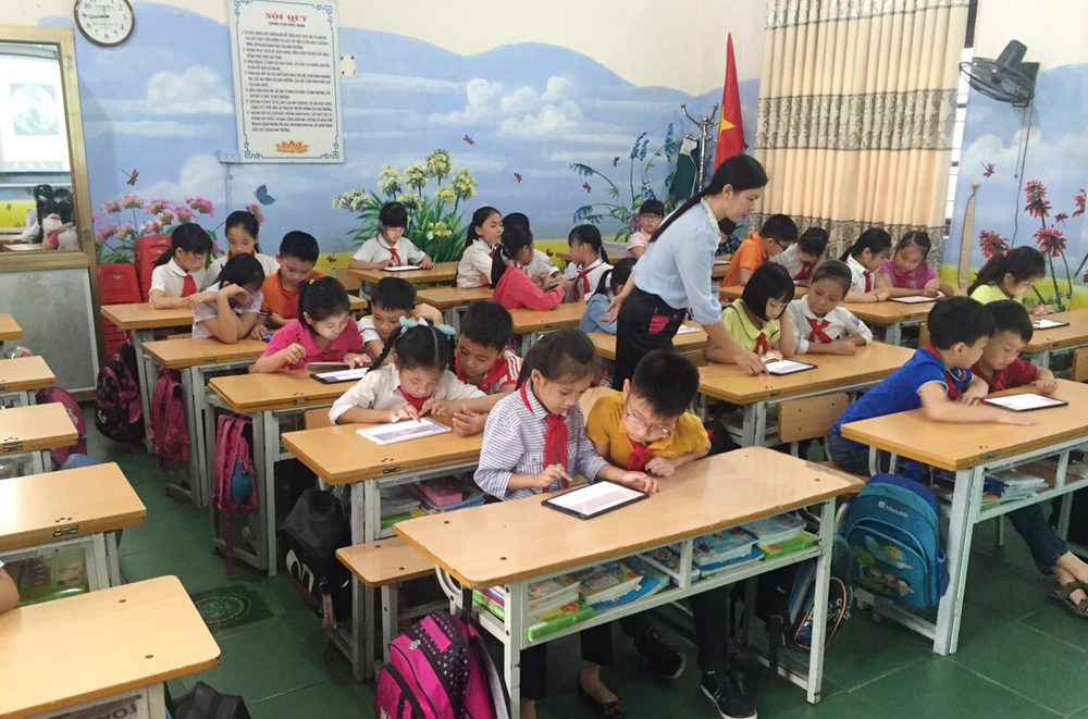 Cô giáo Đào Thị Kiều Trang, Trường Tiểu học Yên Thanh hướng dẫn học sinh sử dụng máy tỉnh bảng học học tập