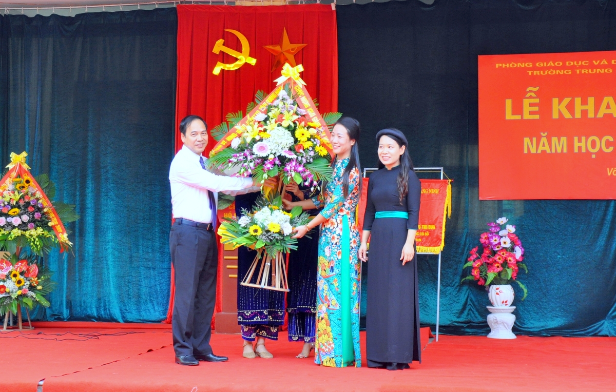 Phó Chủ tịch Thường trực UBND tỉnh Đặng Huy Hậu tặng hoa chúc mừng cô và trò Trường THCS Vô Ngại nhân ngày khai giảng.
