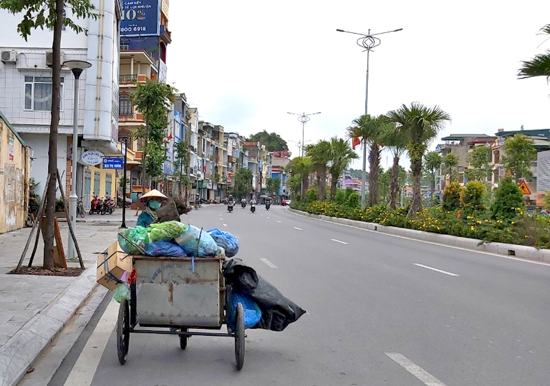 Công nhân công ty Công ty CP Đầu tư và Phát triển môi trường đô thị Quảng Ninh thu gom rác trên đường Nguyễn Văn Cừ. Ảnh: Thu Nguyệt