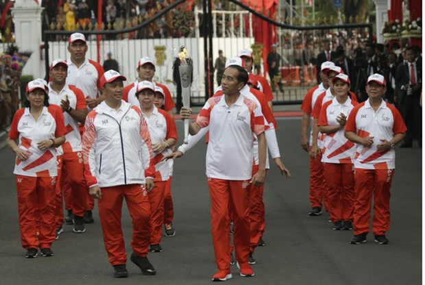 Tổng thống Indonesia Joko Widodo (giữa) cầm ngọn đuốc Thế vận hội châu Á và Bộ trưởng Thanh niên và Thể thao Imam Nahrawi (trái) trong buổi lễ Ngày Độc lập tại Cung điện Merdeka ở Jakarta, ngày 17/8/2018. (Nguồn: AP)