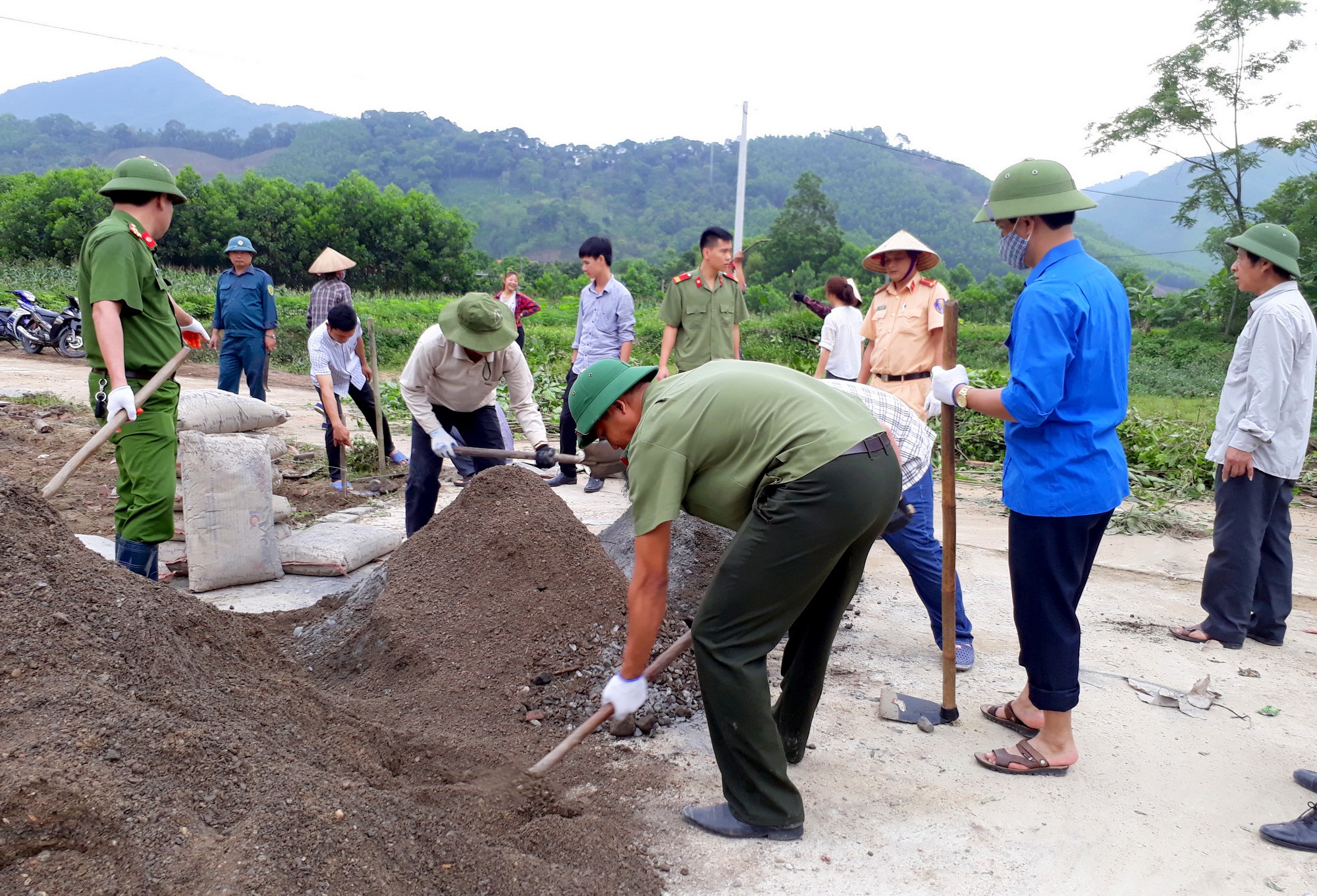 Cán bộ cơ quan Khối MTTQ và các Đoàn thể và CBCS Công an huyện Hoành Bồ giúp nhân dân thôn Khe Mực (xã Tân Dân) đổ bê tông sân nhà văn hóa.