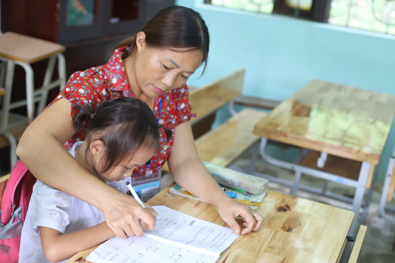 Cô Xoan kèm cặp thêm cho em Trịnh Thị Tươi, học sinh khuyết tật.