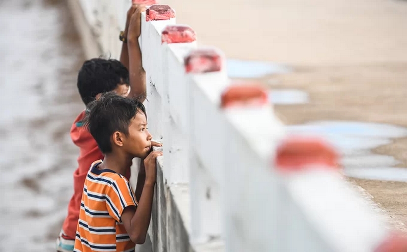 Những đứa trẻ sống gần cánh đồng điện gió nhìn theo đoàn khách du lịch trên cây cầu dẫn ra giữa biển.