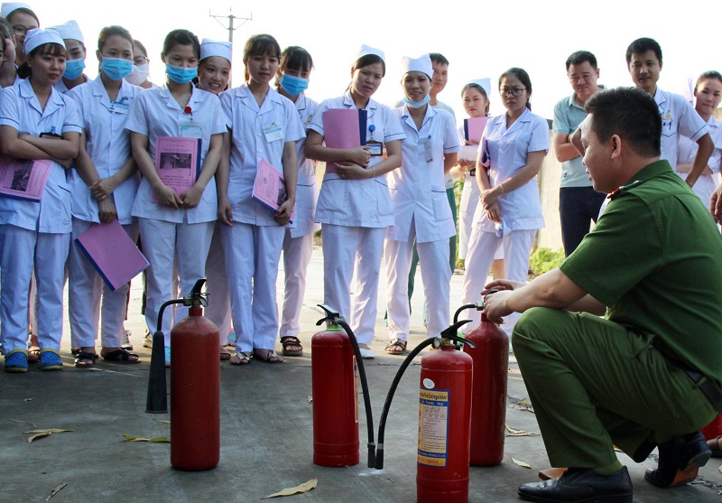 Công an TX Đông Triều hướng dẫn cơ sở y tế tại địa phương sử dụng bình chữa cháy để dập tắt đám cháy.