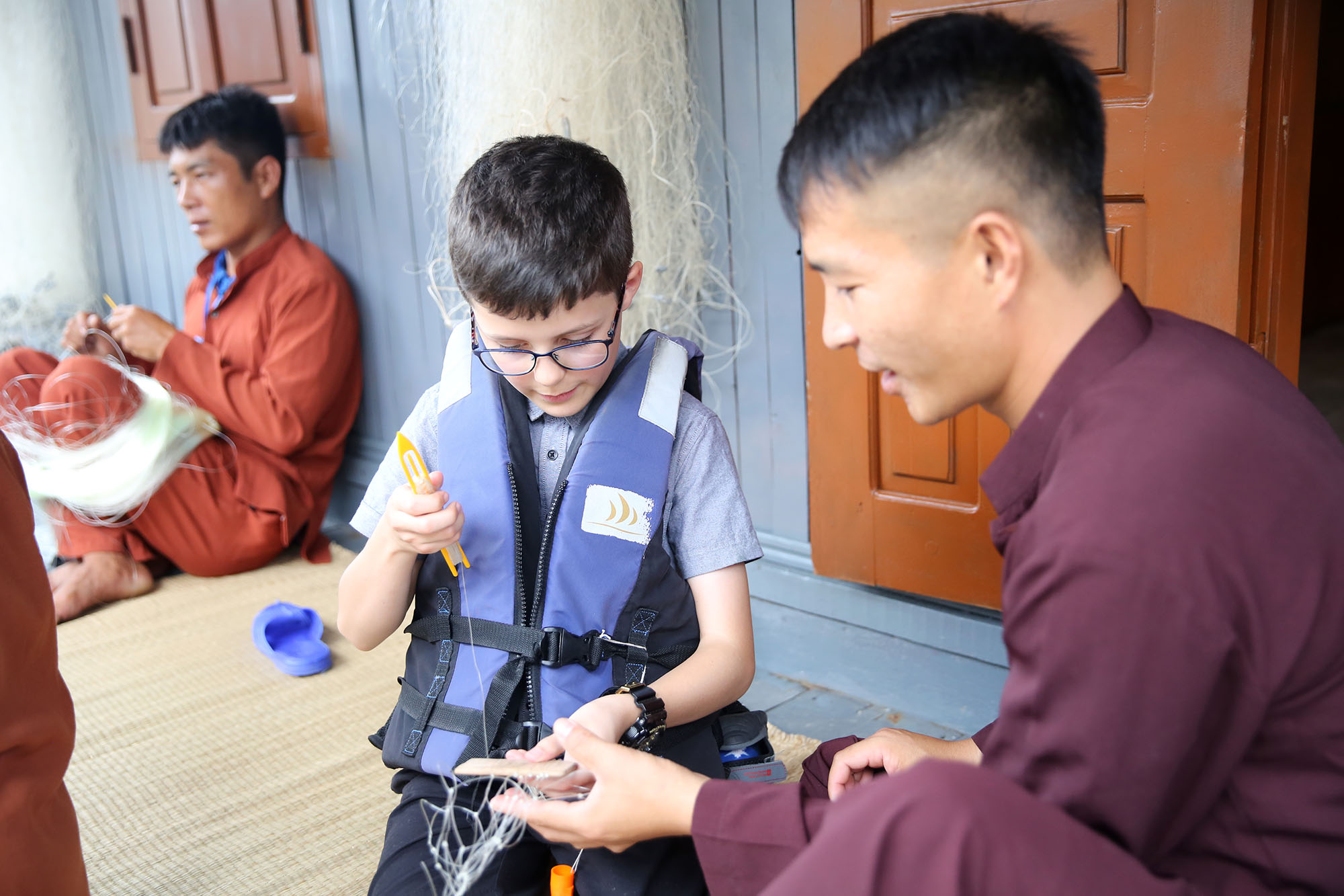 Em bé người nước ngoài thích thú khi được tận tay làm công việc truyền thống của dân chài vùng biển Hạ Long.