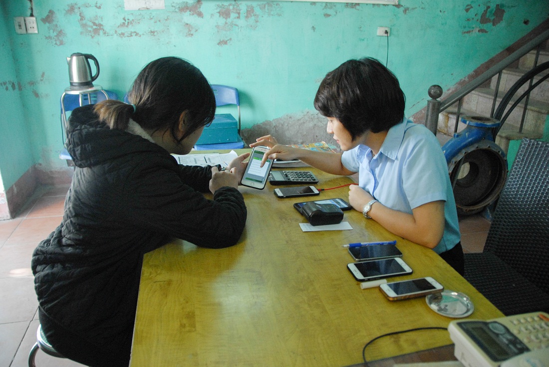 Người dân đến đóng tiền trực tiếp tại trạm khu vực phường Hồng Hải (TP Hạ Long) và được nhân viên thu ngân hướng dẫn dịch vụ đóng tiền qua ngân hàng.